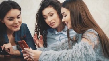 Mutlu çeşitli arkadaşlar öğle yemeği sırasında kafede birlikte telefon kullanarak. Akıllı telefon ekranına bakıyorum. Gülen adam sosyal ağda komik video gösteriyor. Toplantıda iş arkadaşlarına online şaka. Eğlenceli.