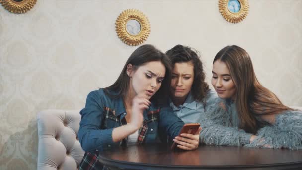 De unga tre goda unga flickorna sitter på ett kafé och spenderar tid på att kommunicera — Stockvideo