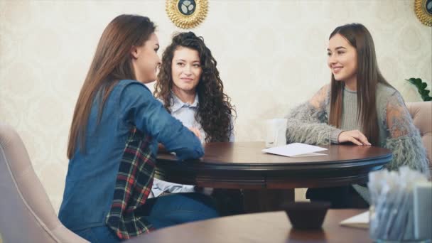 Feliz tres hermosas chicas sentadas en un café con sus novias. Durante esto, cuente y cuente varias historias. Disfrutando del tiempo juntos mientras se relajan en el café . — Vídeos de Stock