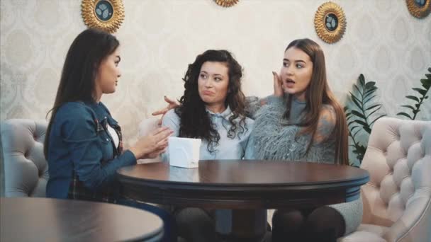 Tres lindas chicas lindas sentadas en un café. Durante esto, charlan y ven directamente en el ojo. Tener el pelo largo negro agradable . — Vídeos de Stock