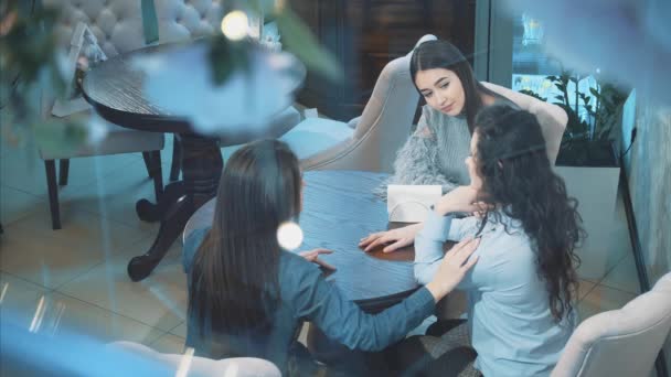 Three young beautiful girls are sitting in a cafe. During this girlfriend communicate. Have nice black long hair. After a long separation. — Stock Video