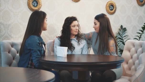 Feliz tres hermosas chicas sentadas en un café con sus novias. Durante esto, cuente y cuente varias historias. Disfrutando del tiempo juntos mientras se relajan en el café. Tener los tres largo negro hermoso — Vídeo de stock