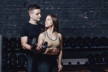 Bir spor kadını kaslı bir egzersiz yapıyor. Kırmızı bir arka plan üzerinde dumbbells ile Fotoğraf kas fitness modeli geliştirme. Güç ve motivasyon.
