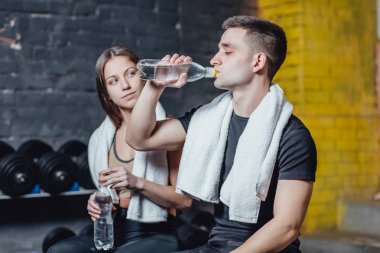 Eğitim sırasında sağlıklı bir genç çiftin portresi. Gençler eğitim sırasında içme rejimine bağlı. Bu esnada spor salonundalar..