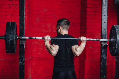 Güçlü bir vücudu olan iyi kaslı bir adam. Spor salonunda egzersizler. Fiziksel dayanıklılık ve gücün başarısı. Yarışmaya hazırlık.