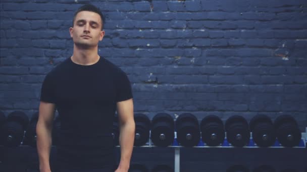 Pemuda sporty mengenakan T-shirt hitam. Seorang pria dengan tubuh olahraga menunjukkan kelas. Selama waktu ini, dia di gym . — Stok Video