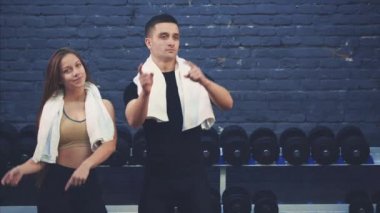Genç sportif çift adam ve kız spor salonunda bulunmaktadır. Bir eğitim seansından sonra, ellerini uzatılmış mesafeye koyarlar ve işaret parmakları uzatılmış bir konuma koyarlar..