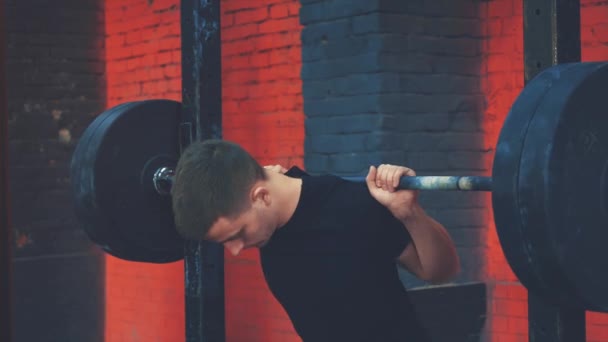 Joven deportista con ropa deportiva en el gimnasio. Tensión para levantar pesas pesadas durante una sesión de entrenamiento. Vestido con una camiseta negra . — Vídeos de Stock