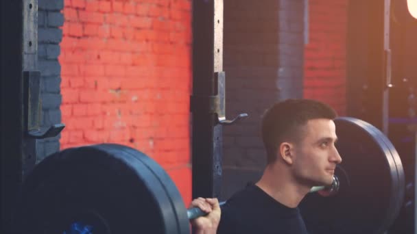 Young sports man wearing sportswear in the gym. Tensioning to lift heavy weights during a training session. Dressed in a black T-shirt. — Stock Video