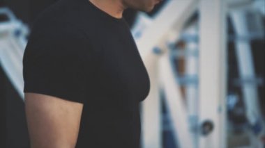 Spor salonunda genç güzellik eğitmeni. Bu süre zarfında, atlet düzenli dumbbells ile eğitim yapar. Siyah bir t-shirt giymiş.