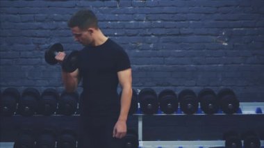 Siyah tişörtlü genç bir çocuk. Spor salonunda büyük bir halter düzenli olarak karanlık bir arka plan üzerinde elleri koçluk. Bu esnada, emzitlerine bayılıyor..