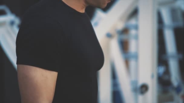 Spor salonunda genç güzellik eğitmeni. Bu süre zarfında, atlet düzenli dumbbells ile eğitim yapar. Siyah bir t-shirt giymiş. — Stok video