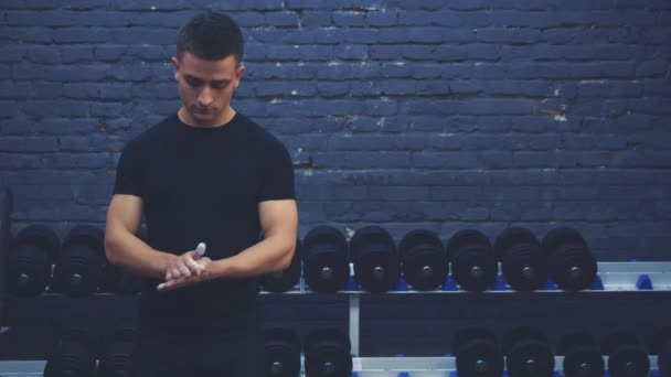 Sportig ung kille klädd i en svart T-shirt. En man med en sportig kropp lägger en hand på handen och blomstrar. Under denna tid är han i gymmet. — Stockvideo