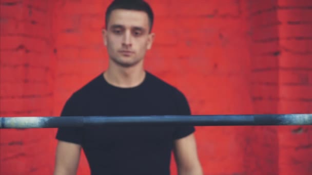 El jinete está de pie con una barra muy pesada en los hombros. Está en la cima y pone un bar. Un joven deportista vestido con una camiseta negra, conoce el gimnasio . — Vídeo de stock