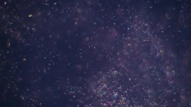 Burbujas claras transparentes de color gris violeta girando y girando aleatoriamente en el aire sobre el oscuro fondo del cosmos . — Vídeo de stock