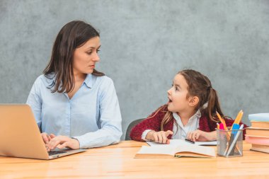 Anne ve bebek gri bir arka plan üzerinde. Bu kadın sırasında, bir dizüstü bilgisayar için çalışan bir çocuk bakarak. Konuşarak, birbirimize bakarak.