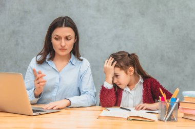 Anne ve kızı gri bir arka plan üzerinde. Bu esnada, annem dizüstü bilgisayarda kızına göstererek soruna bir çözüm buldu. Kız şaşırır ve elini başının üstüne koyar..