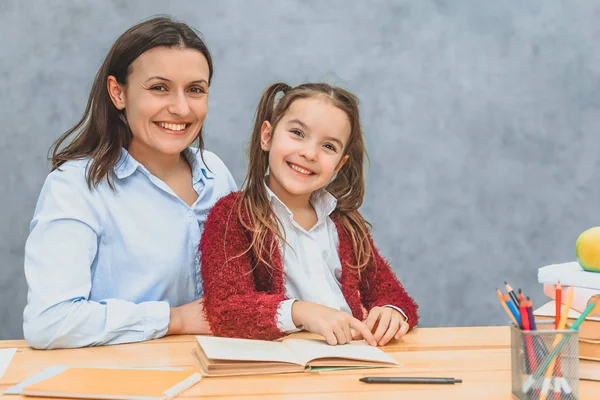 Lächelnde Mutter und Tochter beim Lesen eines Buches. Während dieser Zeit ist es angenehm, mit einem Lächeln in die Kamera zu schauen. — Stockfoto