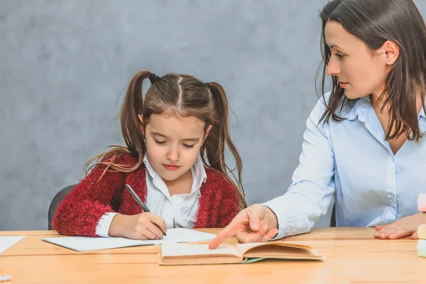 Close up engraçado mãe e filha criança fazendo lição de casa escrever e ler em casa . — Fotografia de Stock