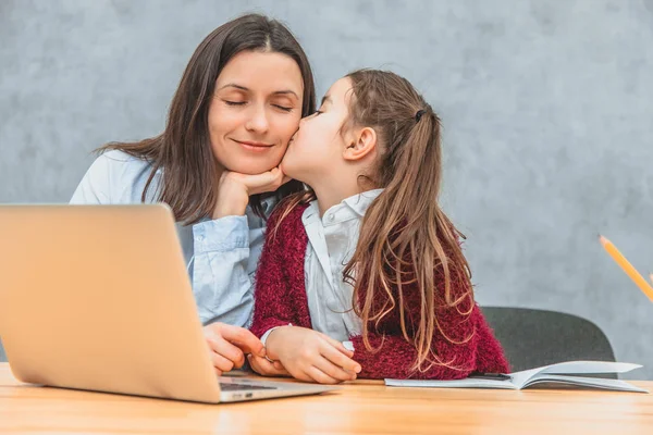 Mom and schoolgirl are sitting at the table. Mom closing her eyes enjoys the sucking of her daughter. Sincere emotions. Love.