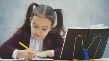 Akıllı, özenli kız öğrenci masada otururken ev ödevi yapar. Bu yazı sırasında, egzersiz kitapta görünüyor.