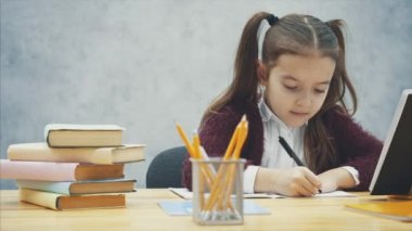 Akıllı kız öğrenci masada otururken ev ödevi yapar. Bu yazı sırasında, kalem sarı bir renk alır.