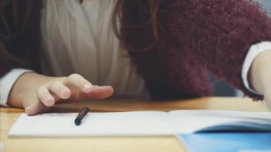 Masadaki kız öğrenci nin elini yakın. Gri arka plan.