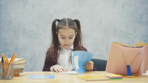 Intelligentes, aufmerksames Schulmädchen erledigt Hausaufgaben, während sie am Tisch sitzt. Während dieses Schreibens sieht die Übung im Buch aus. — Stockvideo