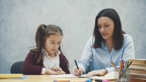 Jeune enseignant aidant l'enfant à écrire leçon ou mère et fille apprenant à écrire, mère enseignant la petite fille devoirs isolés sur fond blanc, Éducation étude maison école mère jour concept — Video