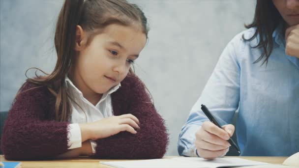 Joven maestro ayudando a los niños a escribir lección o madre e hija aprendiendo a escribir, madre enseñando tarea de niña aislada en fondo blanco, educación estudio hogar escuela madres día concepto — Vídeos de Stock