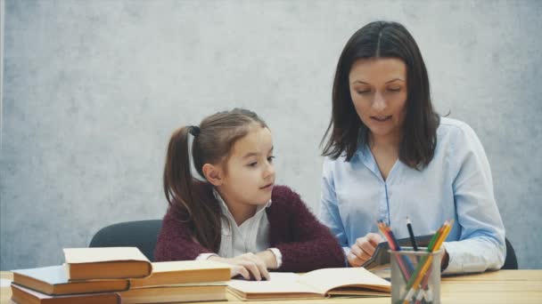 Mãe e filha contam com um dever de casa calculadora preta. Durante isso em um fundo cinza . — Vídeo de Stock