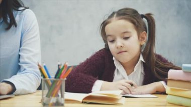 Gri bir arka plan üzerinde anne ve kızı kapatın. Bu esnada, genç bir anne dizüstü bilgisayarda çalışıyor..