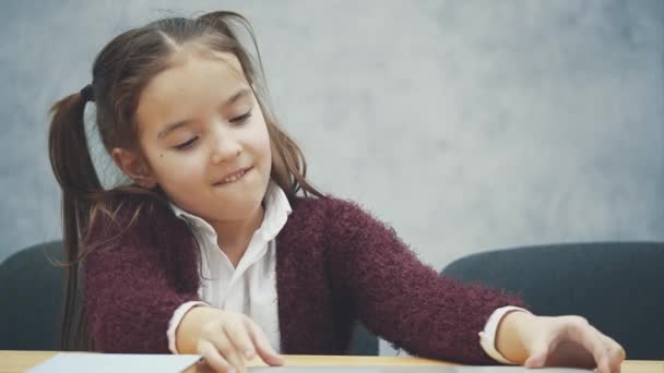 Porträtt av glad söt smart flicka sitter med bibba böcker och laptop vid bordet, kopia utrymme. Utbildning och utveckling koncept — Stockvideo