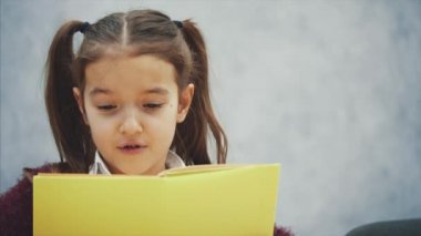 Gri bir arka plan üzerinde genç bir kız öğrenci. Eğitim ve okul kavramları - masada birçok kitap ile gülümseyen kız öğrenci kız.