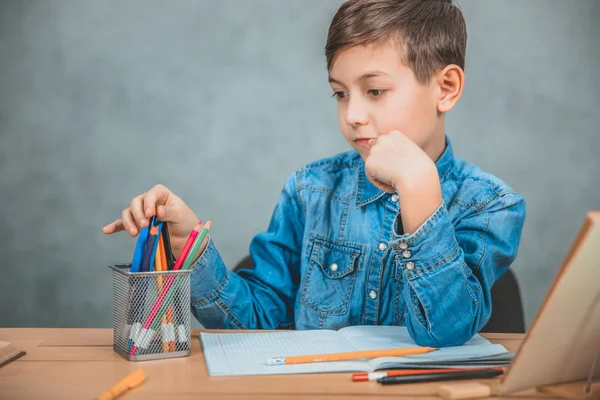 Schoolkid välja färgglada penna från korgen. Tänkande, oncentrerade. — Stockfoto