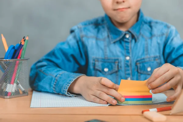 Seříznutý kousek zvědavé žáky seděl u stolu s knihami a počítal barevné nálepky. — Stock fotografie