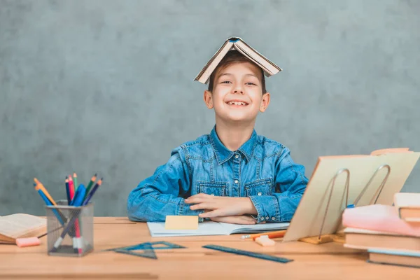 Divertido alumno jugando alrededor de poner libro como un techo en su cabeza, sonriendo. Emociones, comportamiento tonto . — Foto de Stock