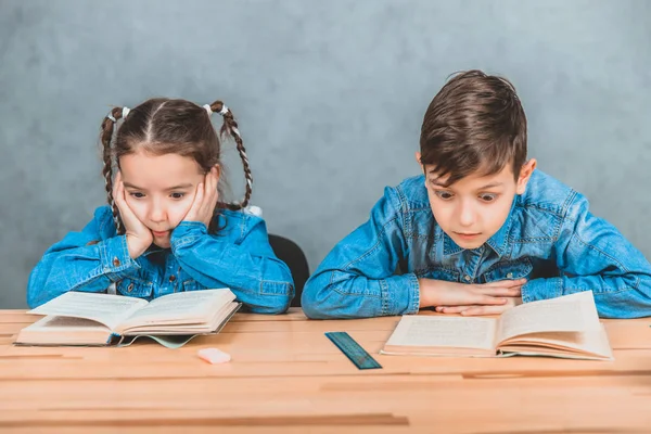 Intelligente Jungen und Mädchen, die völlig in den Prozess des Lesens verwickelt sind. — Stockfoto
