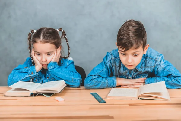 Garoto e menina inteligente totalmente envolvidos no processo de leitura . — Fotografia de Stock