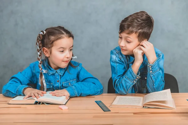 Niño y niña inteligentes totalmente involucrados en el proceso de lectura . — Foto de Stock