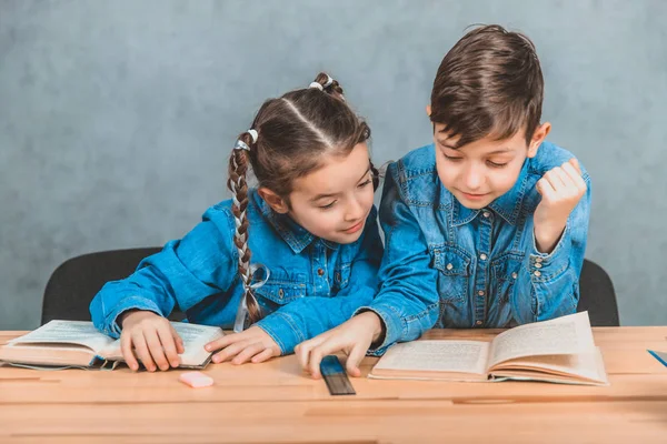 Garoto e menina inteligente totalmente envolvidos no processo de leitura. Menino está apontando para algo interessante em seu livro . — Fotografia de Stock