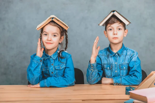 Divertidos alumnos jugando alrededor poniendo libros como un techo en sus cabezas, levantando las manos, mirando curiosamente. Emociones, comportamiento tonto . — Foto de Stock