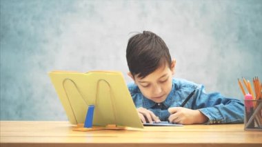 Mavi kot t-shirt yazma genç konsantre okul çocuk, kitap sahibi üzerinde kitaptan metin kopyalama.