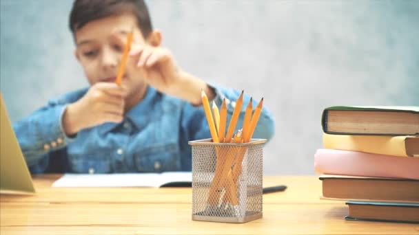 Suddig skolpojke når penna från korgen i framkant, understrykning något med linjal. — Stockvideo
