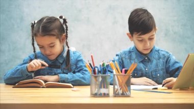 Meraklı küçük kız öğrenci kitabını inceliyor, sonra bir loupe ile kardeşi, gülümseyerek. Etrafta oynuyorlar, gaddarlık yapıyorlar..