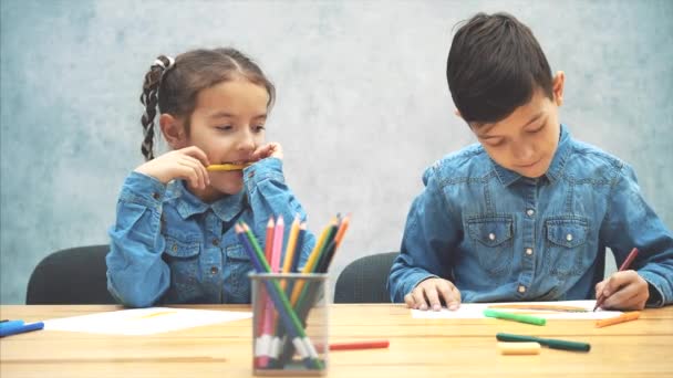 Rozkošný, inspirovaný bratr a sestra se učí kreslit. Legrační dívka držící v zubech značku. — Stock video