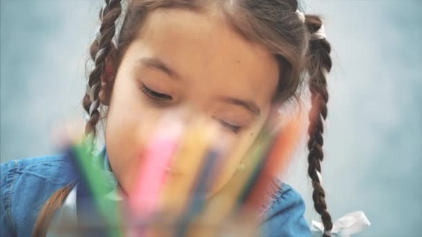Χαριτωμένο δημιουργικό κορίτσι με κοτσίδες φθάνει ένα μολύβι από το καλάθι και το σχέδιο. Θολά μολύβια στην πρώτη γραμμή. — Αρχείο Βίντεο