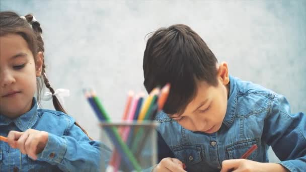 Mignon fille créative et garçon dessinent, atteignant crayons du panier . — Video