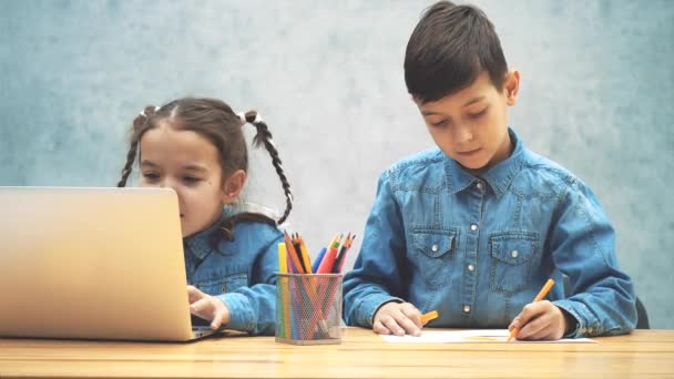 Menina encantadora está envolvida no jogo de computador, seu irmão está desenhando e corrigindo-a, ajudando a jogar . — Vídeo de Stock