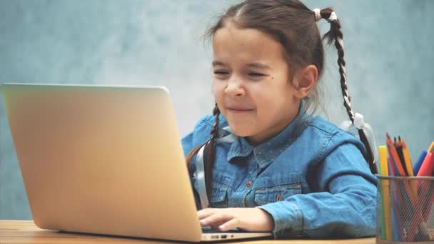Прекрасна дівчина з кісками з ентузіазмом грає в гру на ноутбуці . — стокове відео
